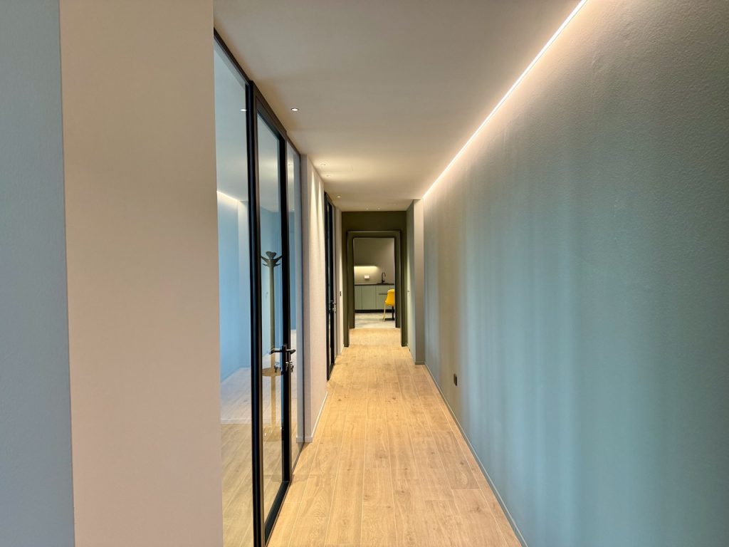 Corridoio con vetrate a telaio nero e luce linear