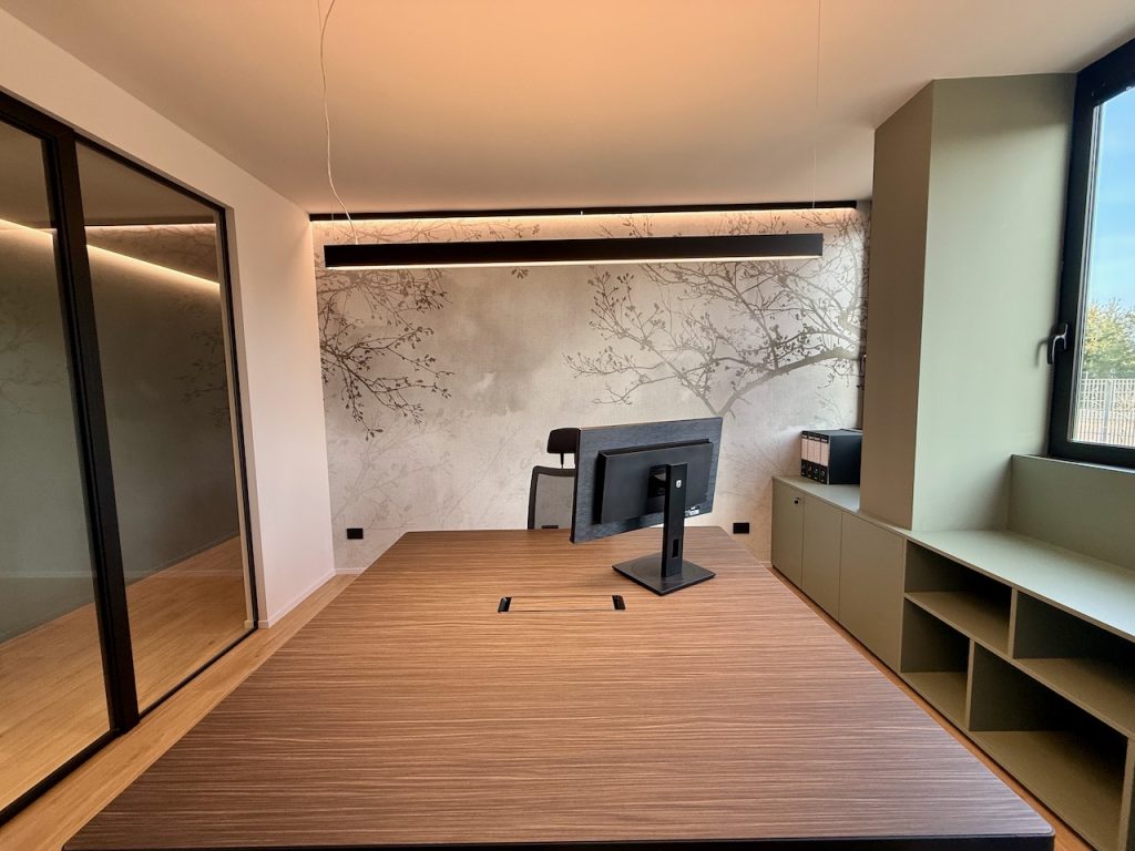 Ufficio con rivestimento a rami chiari e tavolo in essenza